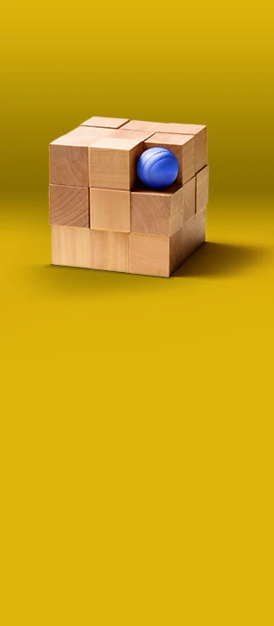 Cubo composto da blocchi di legno su sfondo giallo, con una sfera blu incastonata in uno degli angoli.