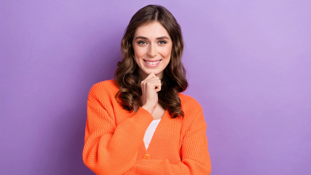 Ragazza sorridente con braccia incrociate e dito sul mento