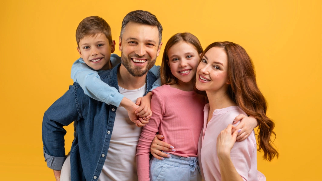 Mamma, papà e due bambini sorridenti abbracciati