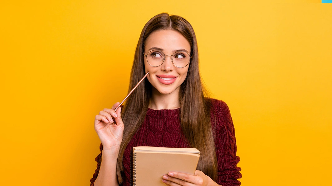 Ragazza sorridente con in mano un quaderno e una matita